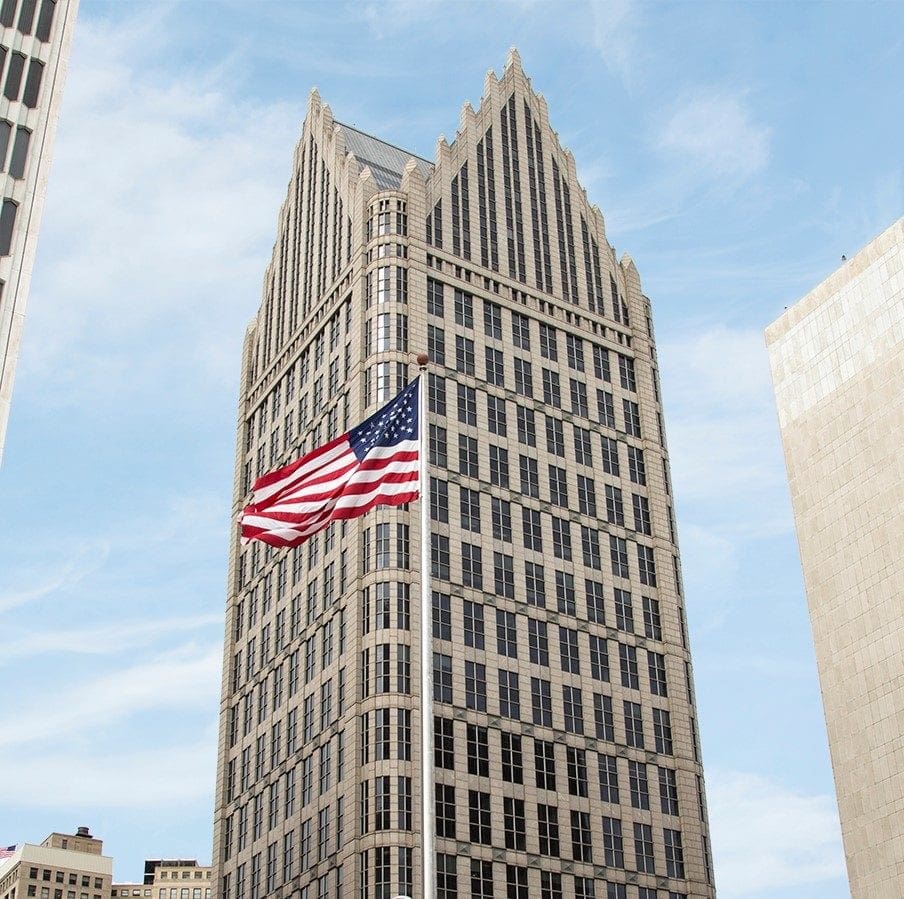 An American flag blows in the wind in front of the Ally Building in Detroit
